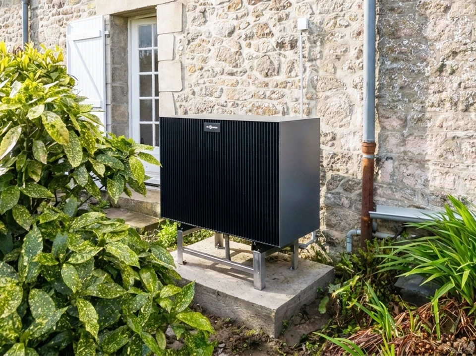 Pompe à chaleur air/eau monobloc noire installée en extérieur, fixée sur socle béton avec châssis inox