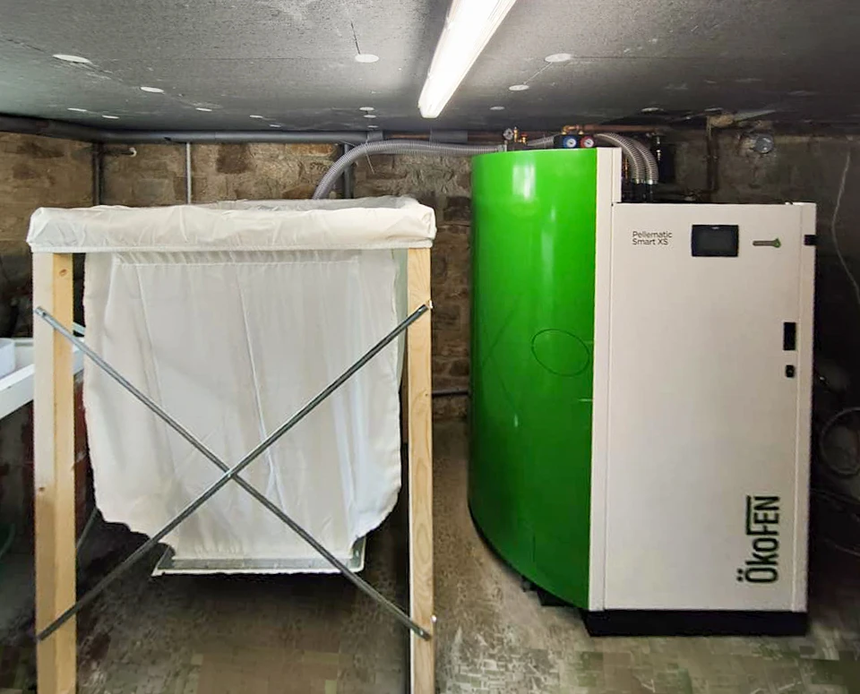 Pompe à chaleur air/eau monobloc noire installée en extérieur, fixée sur socle béton avec châssis inox